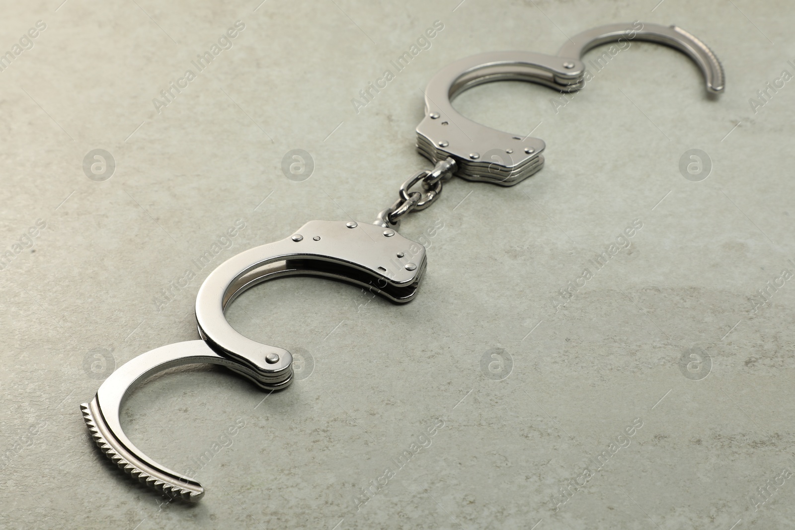 Photo of Classic chain handcuffs on grey table, closeup