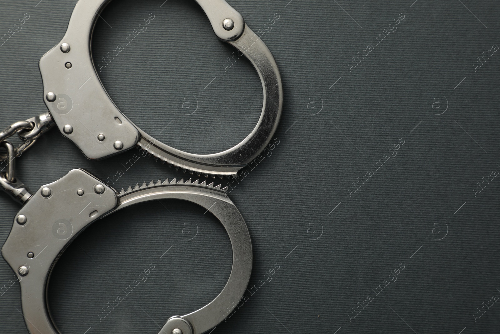 Photo of Classic chain handcuffs on black background, top view. Space for text