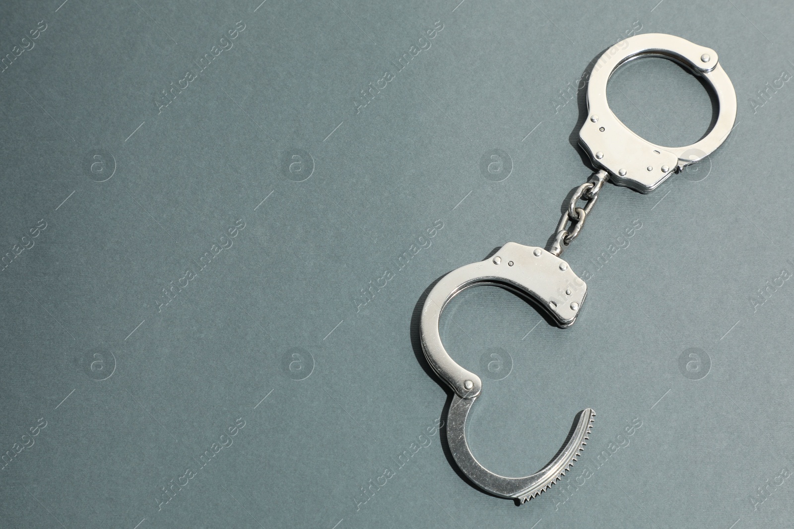 Photo of Classic chain handcuffs on grey background, top view. Space for text