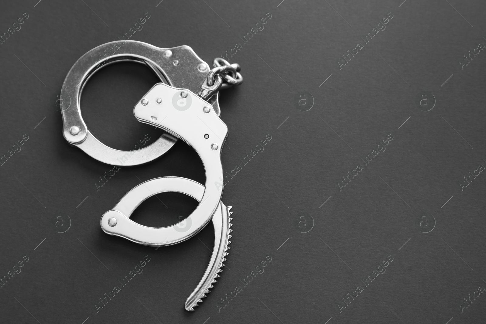 Photo of Classic chain handcuffs on black background, top view. Space for text