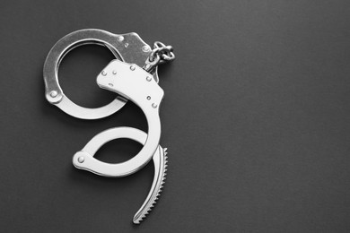 Photo of Classic chain handcuffs on black background, top view. Space for text