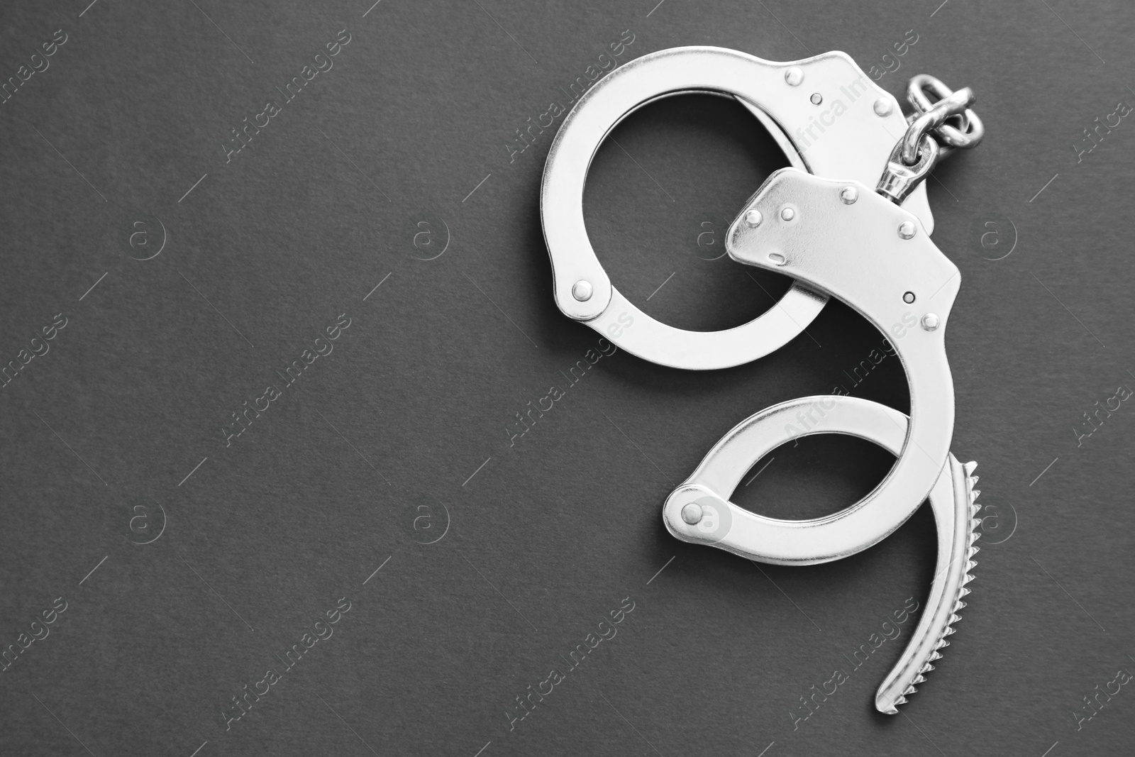 Photo of Classic chain handcuffs on black background, top view. Space for text