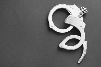 Photo of Classic chain handcuffs on black background, top view. Space for text