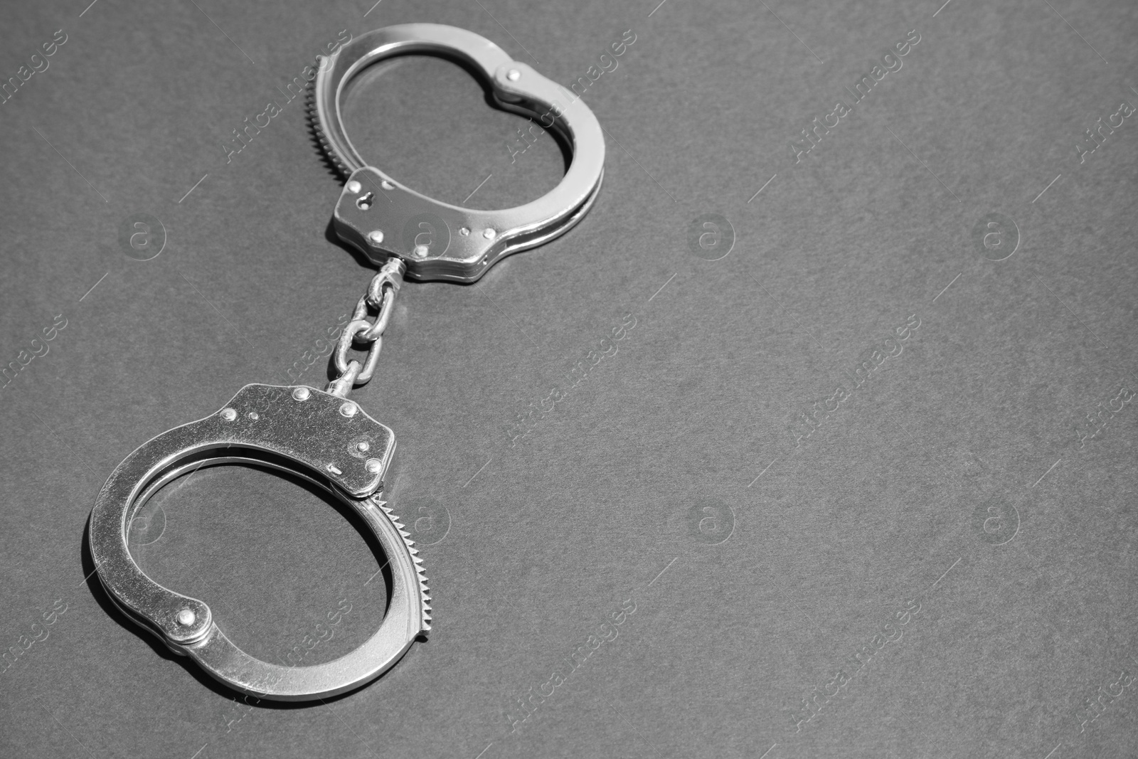 Photo of Classic chain handcuffs on black background, closeup. Space for text