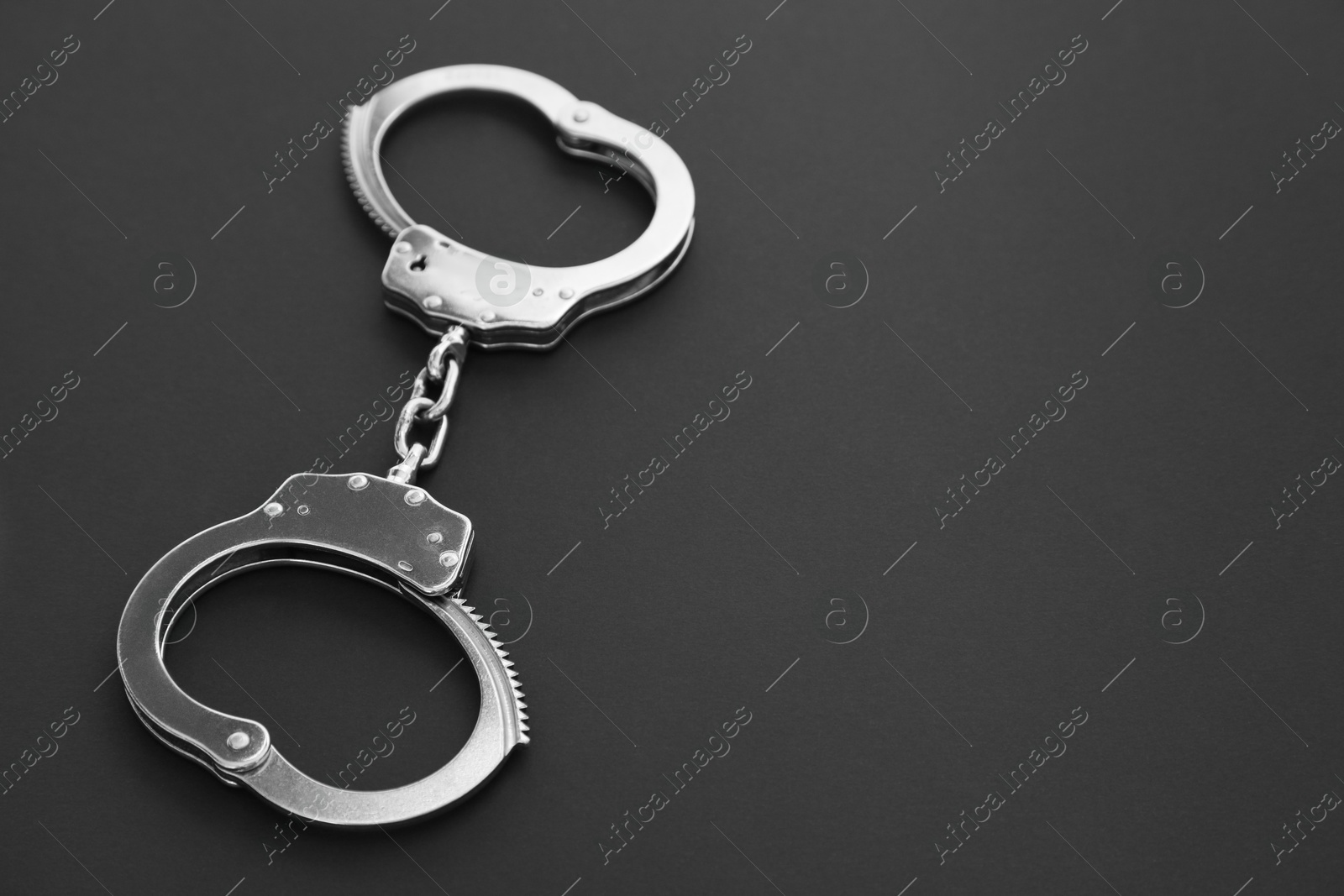 Photo of Classic chain handcuffs on black background, closeup. Space for text