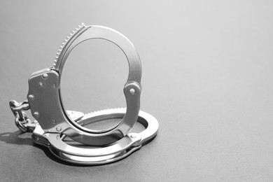 Photo of Classic chain handcuffs on grey background, closeup. Space for text