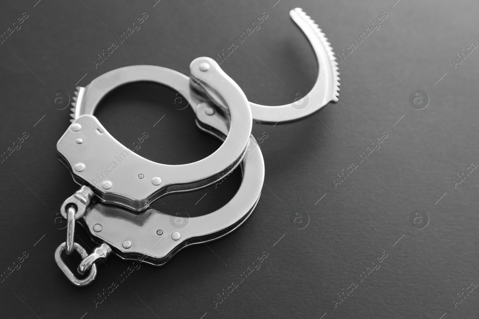 Photo of Classic chain handcuffs on black background, closeup. Space for text