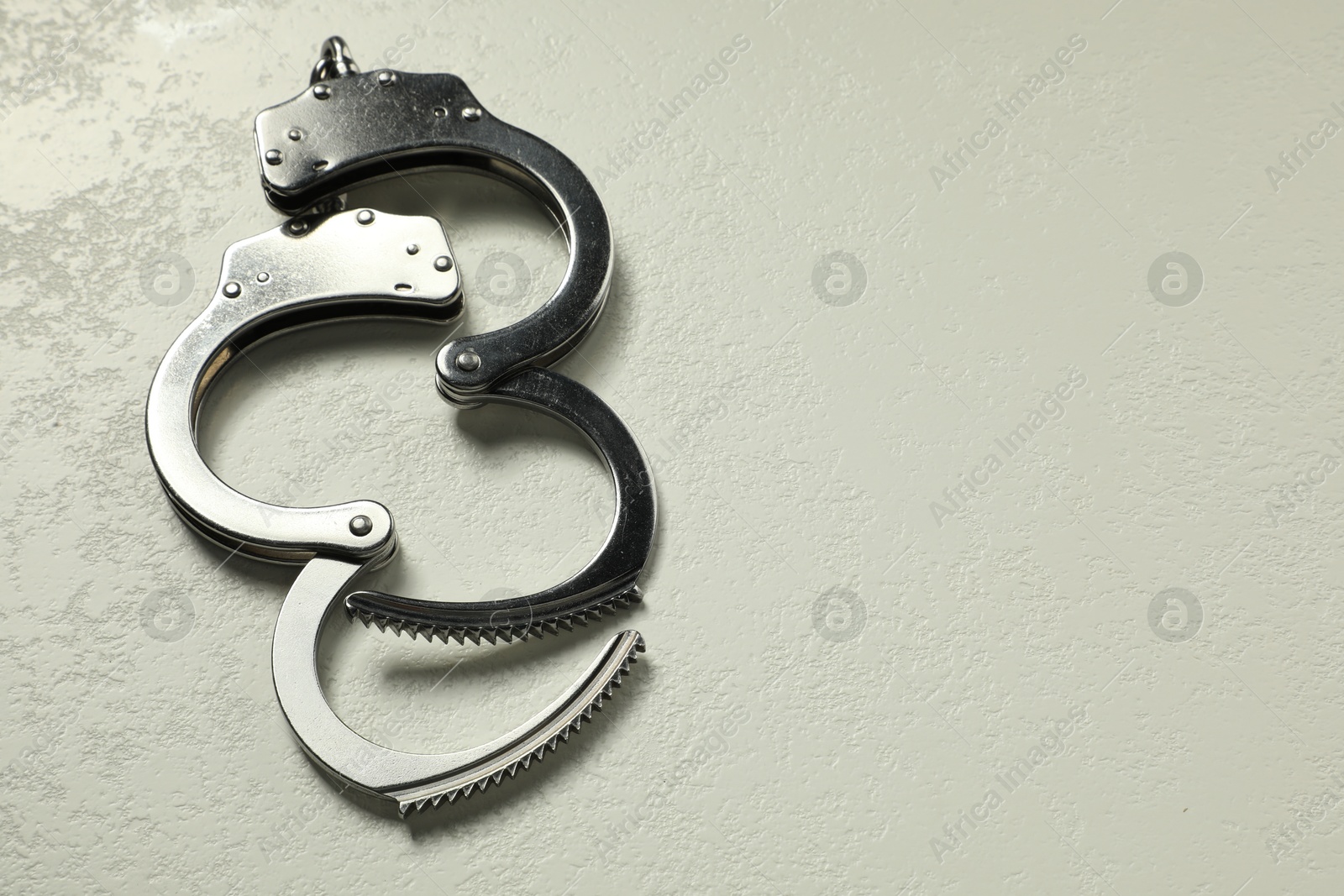 Photo of Classic chain handcuffs on white table, closeup. Space for text