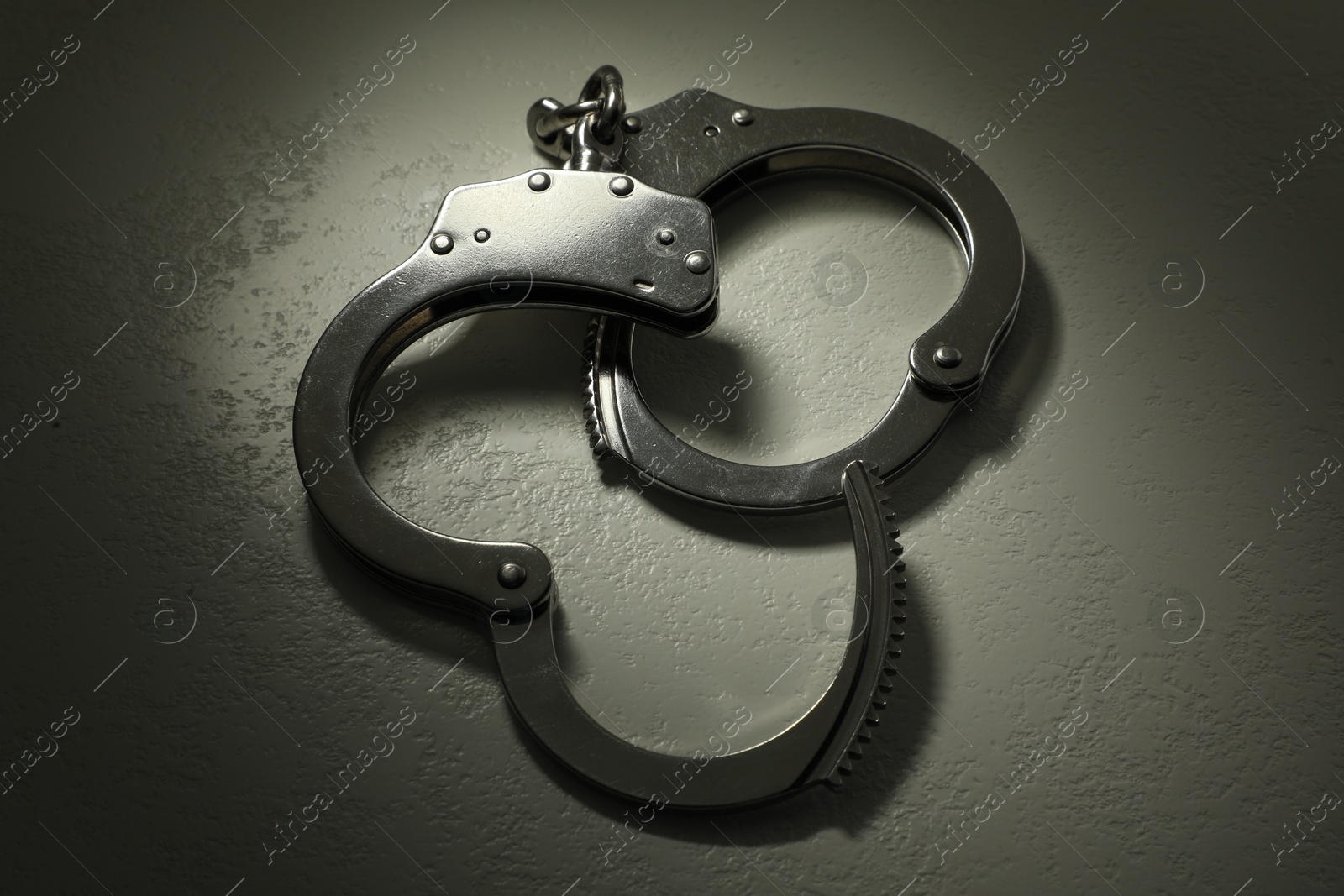 Photo of Classic chain handcuffs on grey table, closeup