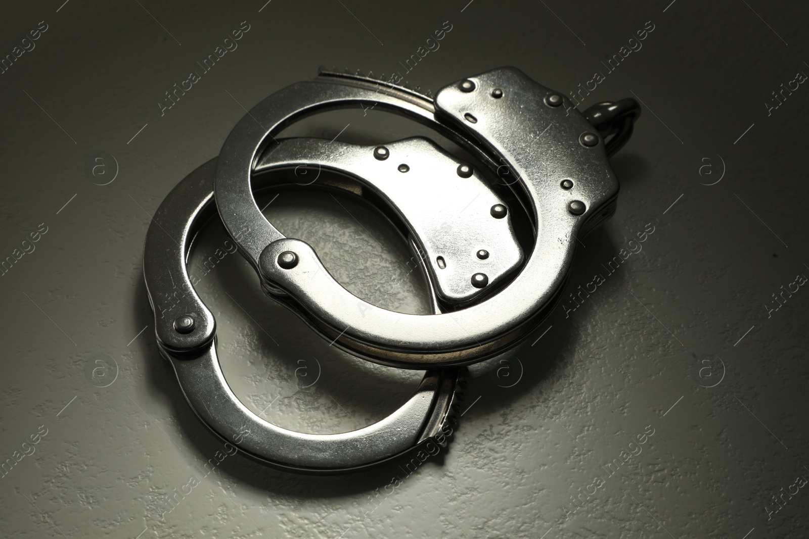 Photo of Classic chain handcuffs on grey table, closeup