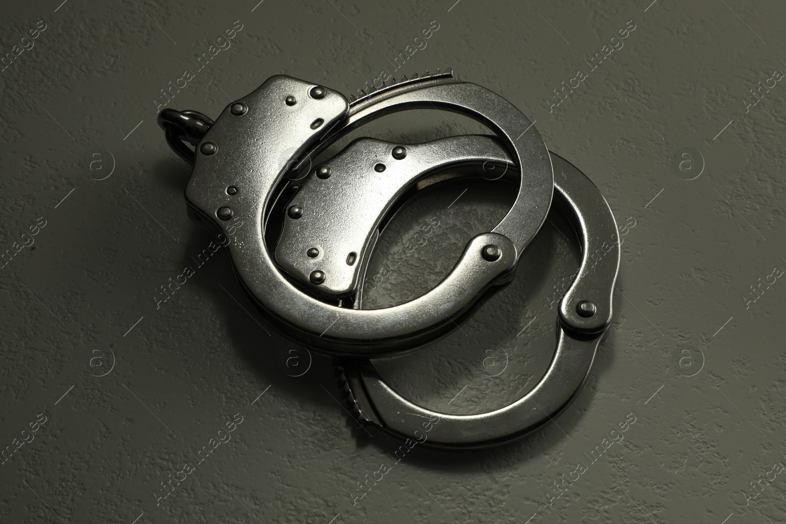 Photo of Classic chain handcuffs on grey table, closeup