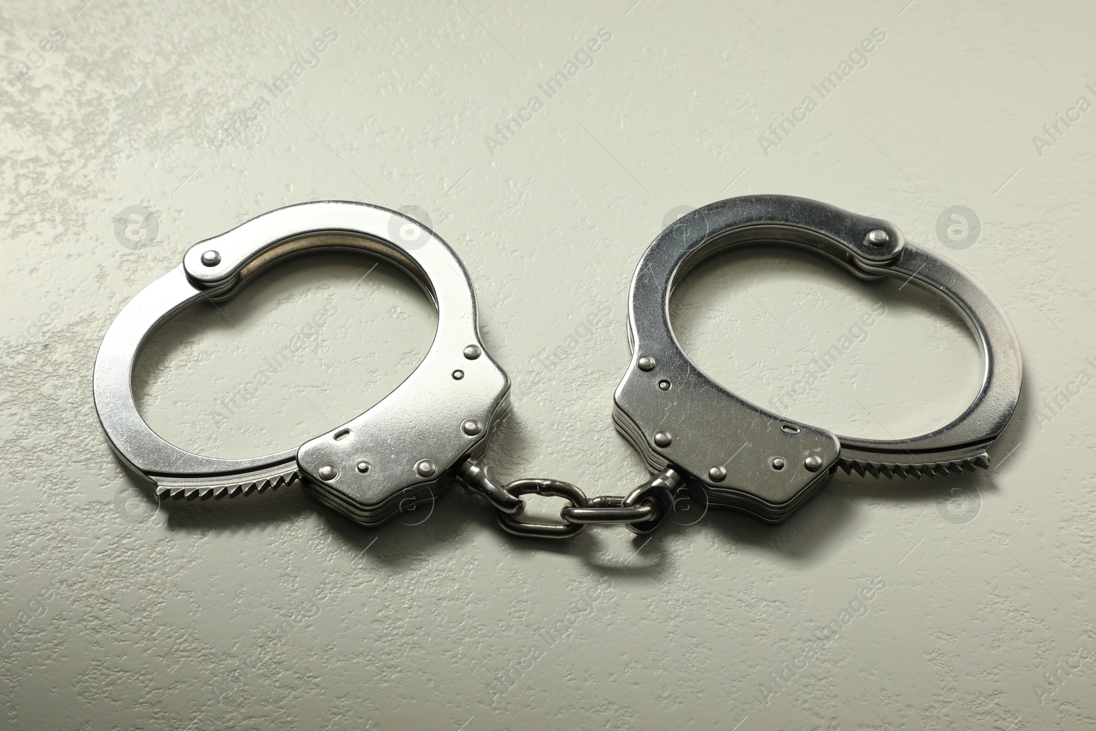 Photo of Classic chain handcuffs on white table, closeup