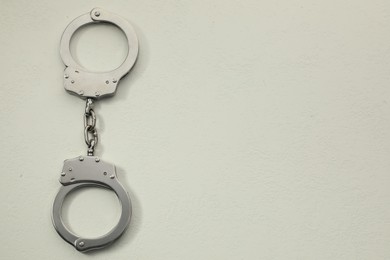 Photo of Classic chain handcuffs on white table, top view. Space for text