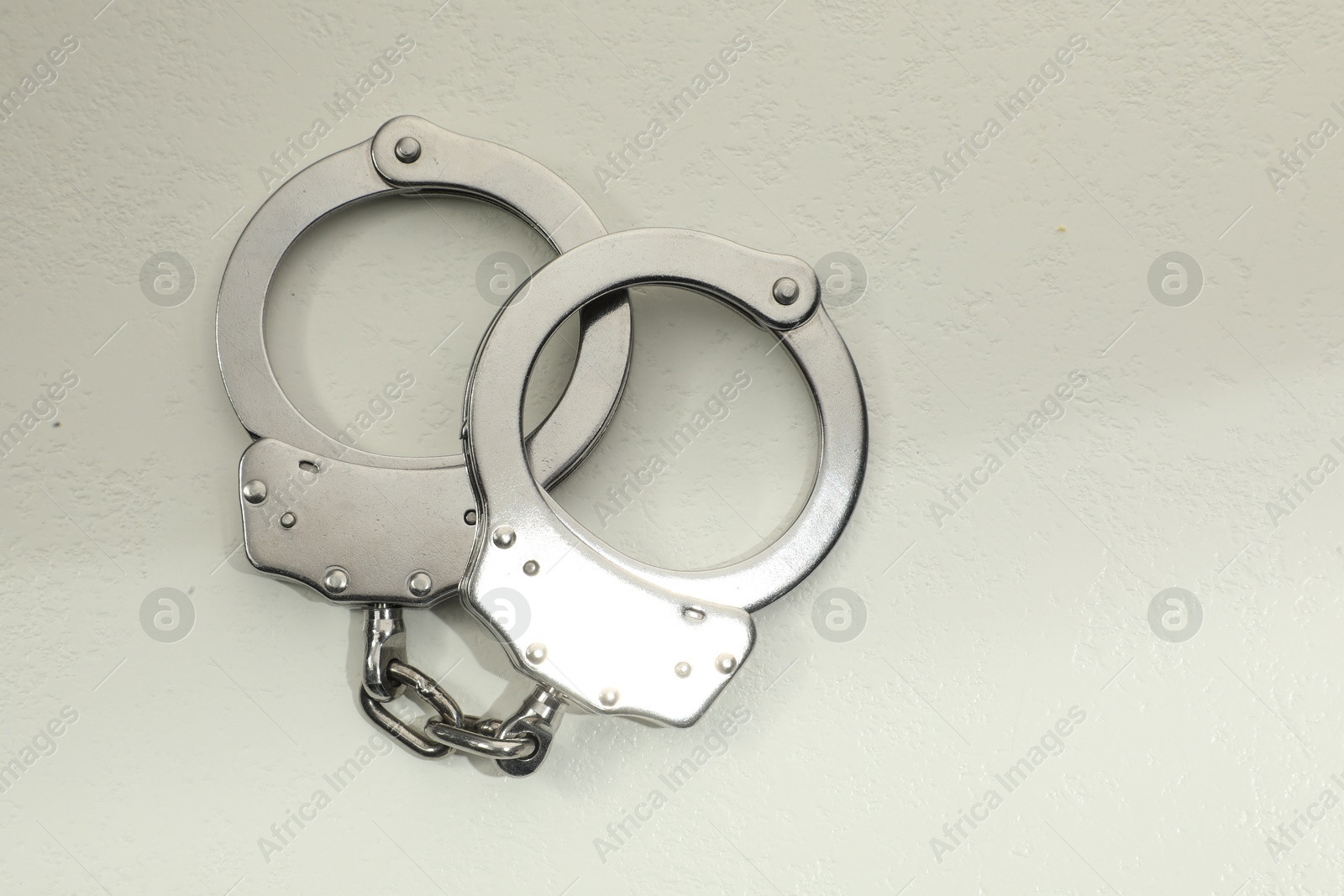 Photo of Classic chain handcuffs on white table, top view. Space for text