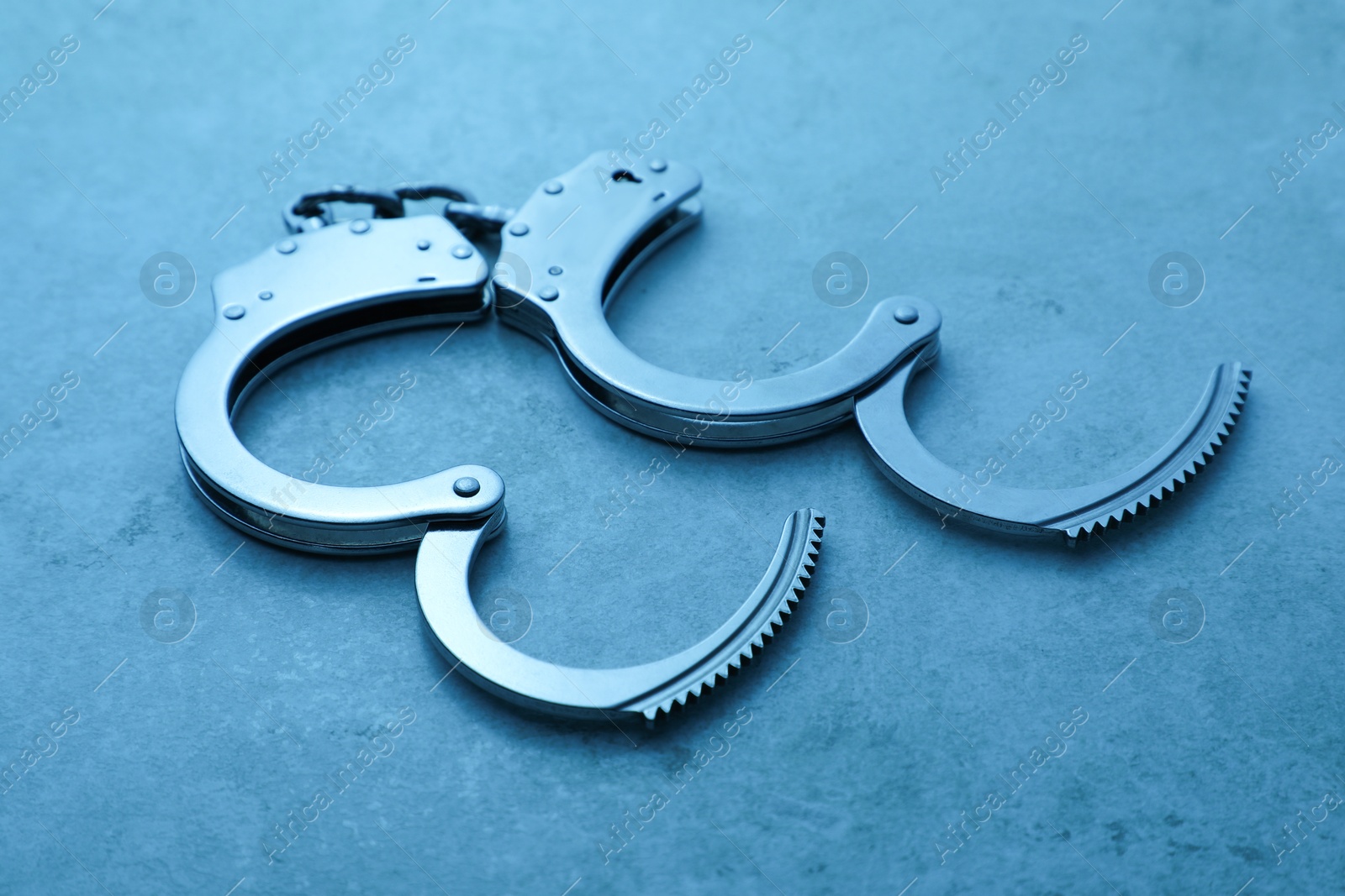 Photo of Classic chain handcuffs on table, closeup. Color toned