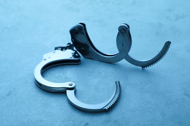 Photo of Classic chain handcuffs on table, closeup. Color toned