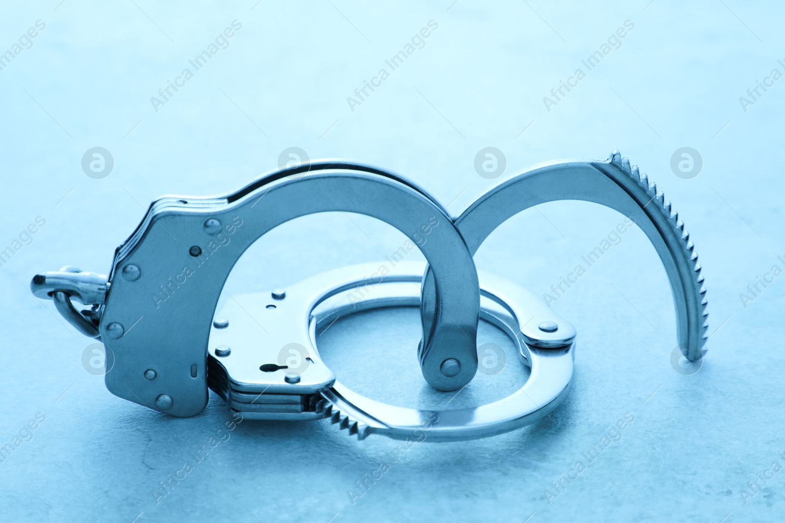 Photo of Classic chain handcuffs on table, closeup. Color toned