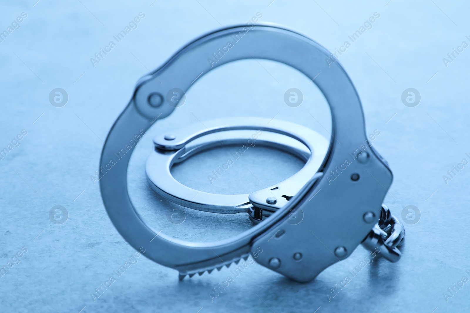 Photo of Classic chain handcuffs on table, closeup. Color toned