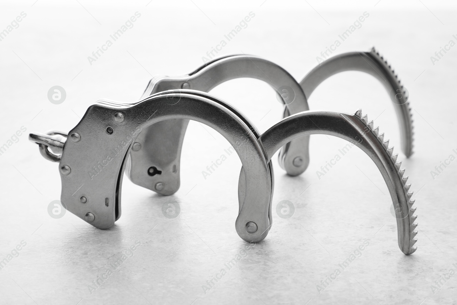 Photo of Classic chain handcuffs on light grey table, closeup