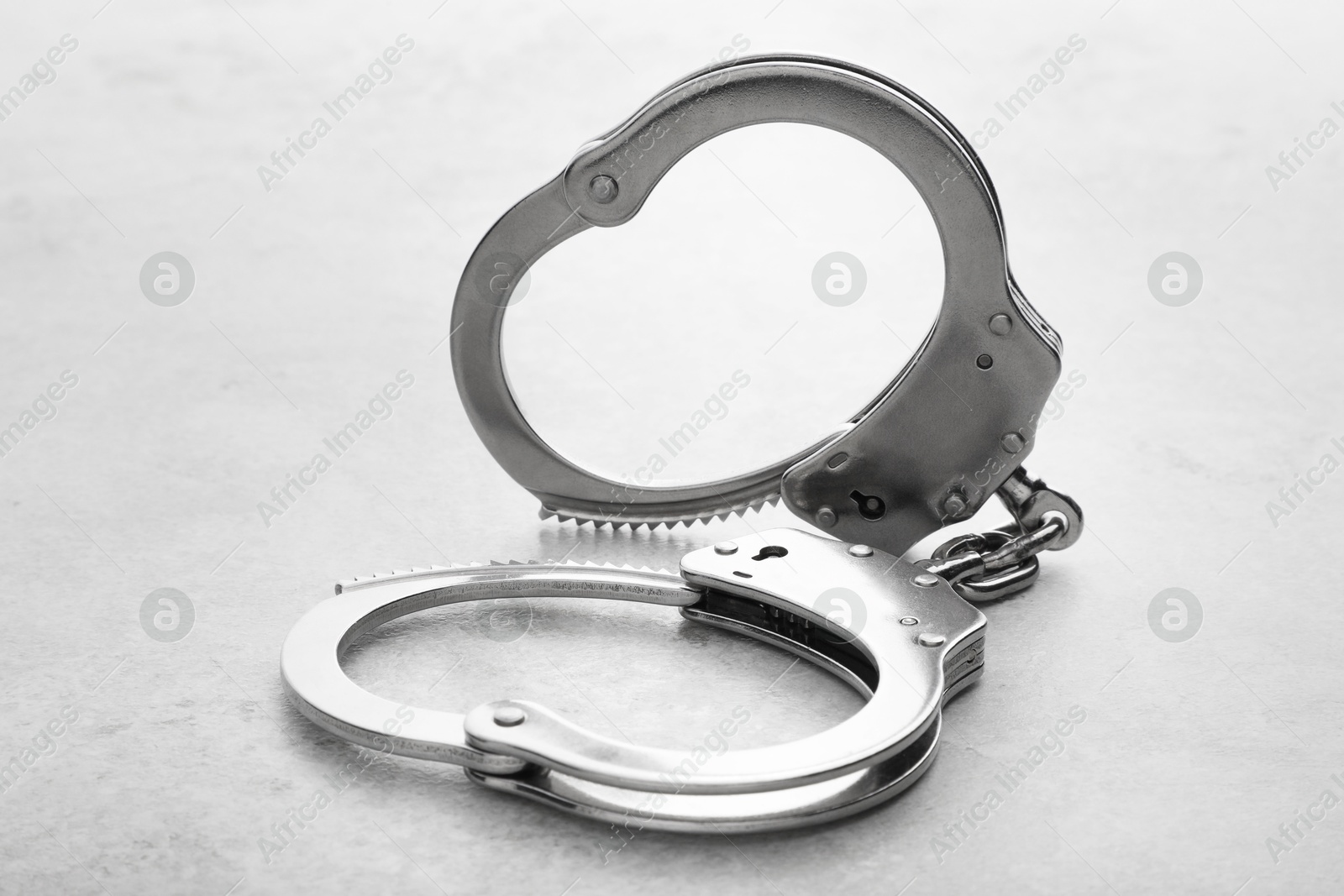 Photo of Classic chain handcuffs on light grey table, closeup