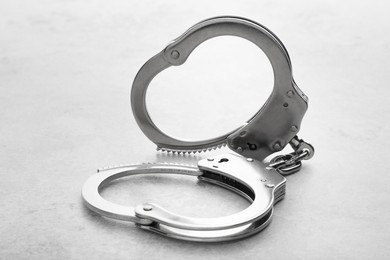 Photo of Classic chain handcuffs on light grey table, closeup