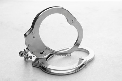 Photo of Classic chain handcuffs on light grey table, closeup