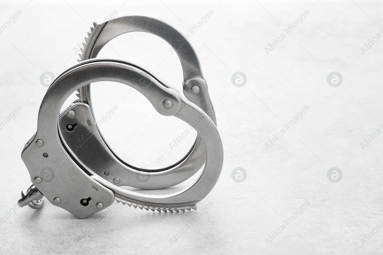 Photo of Classic chain handcuffs on light grey table, closeup. Space for text