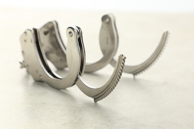 Photo of Classic chain handcuffs on light grey table, closeup