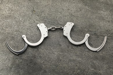 Photo of Classic chain handcuffs on grey table, top view