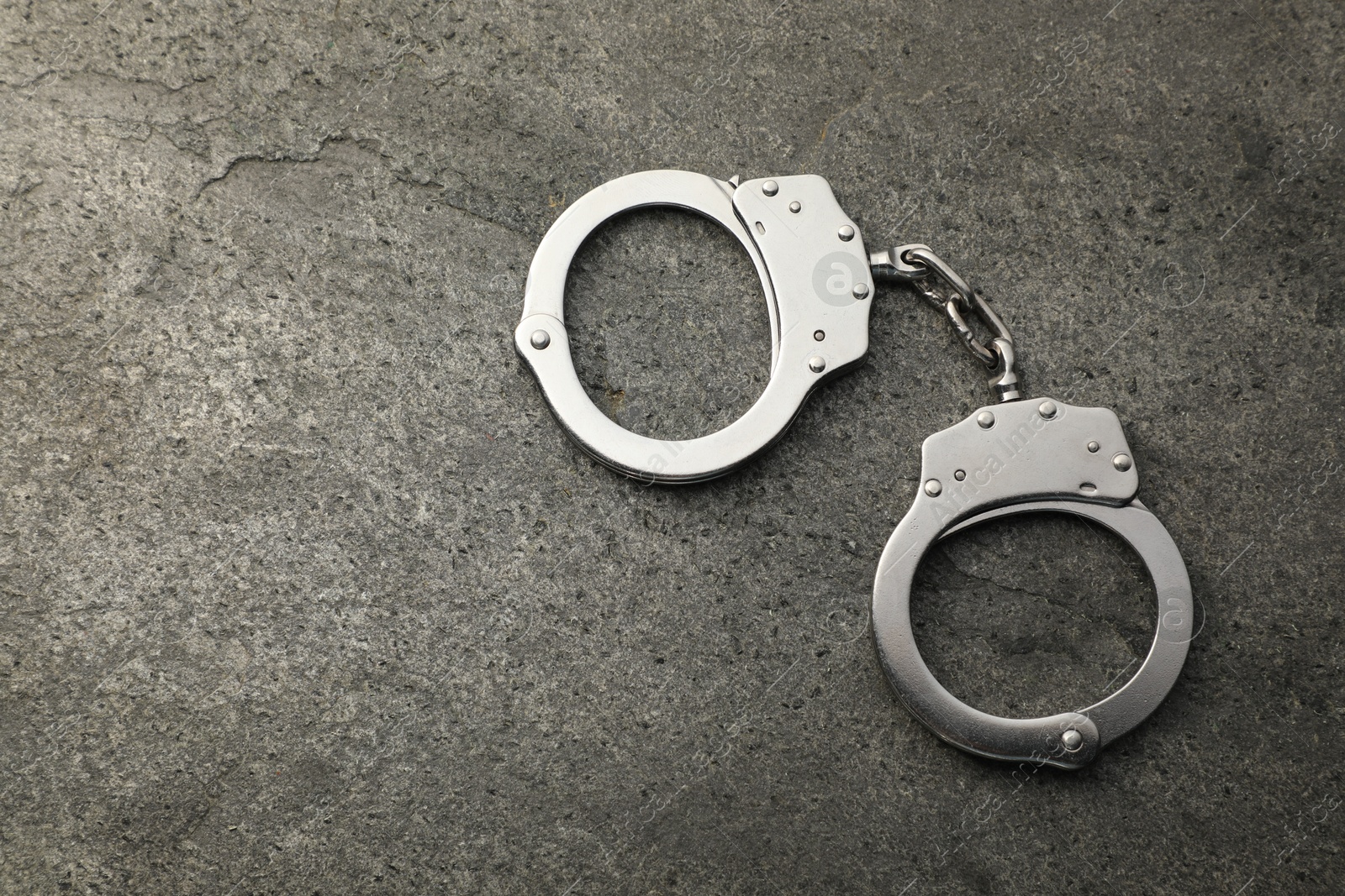 Photo of Classic chain handcuffs on grey table, top view. Space for text