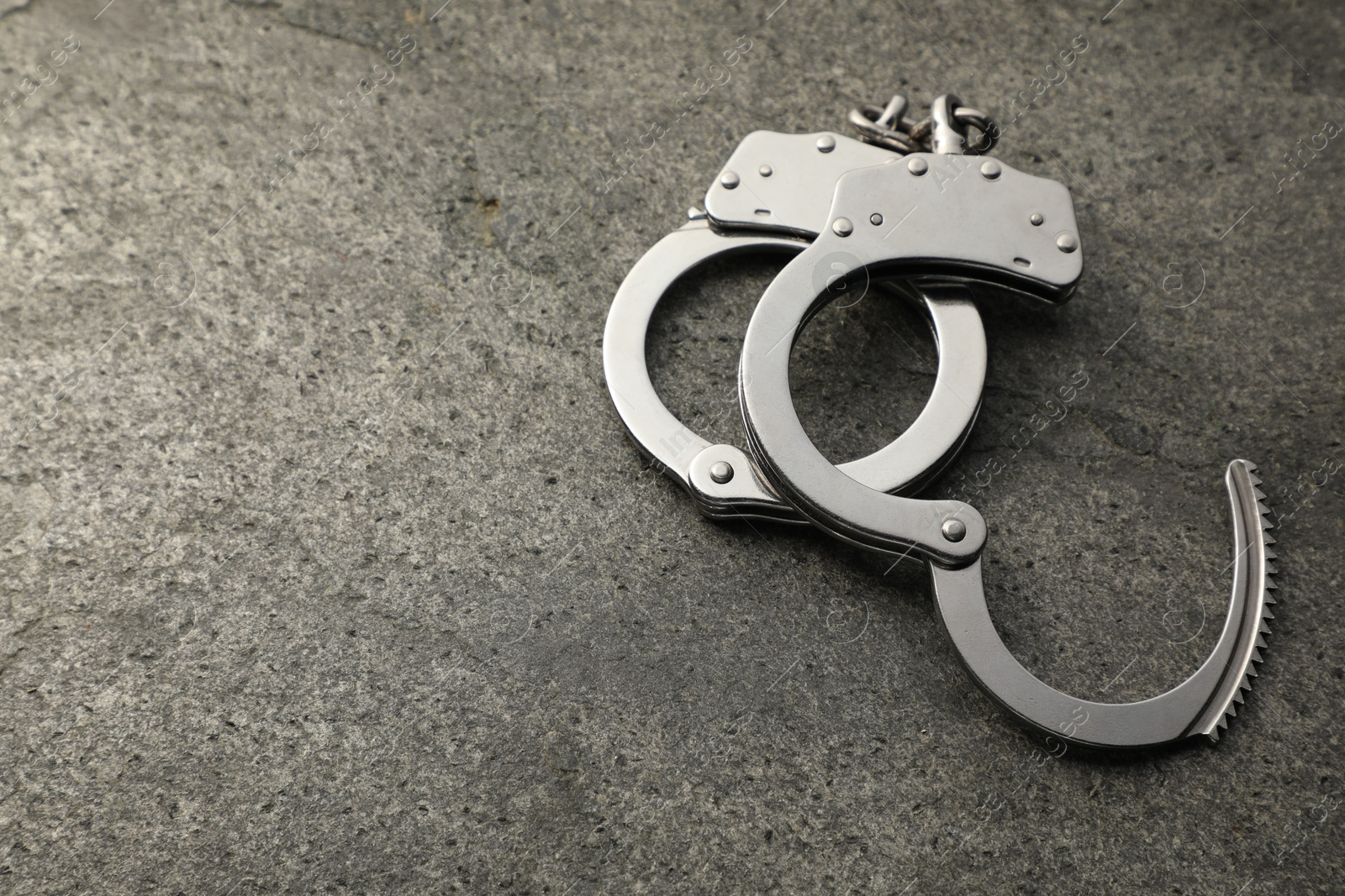 Photo of Classic chain handcuffs on grey table, space for text