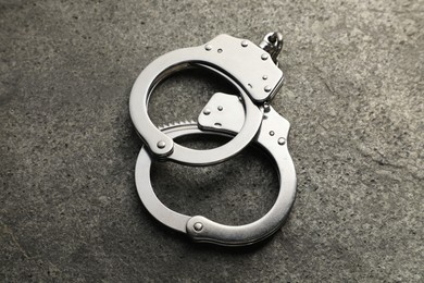 Photo of Classic chain handcuffs on grey table, closeup