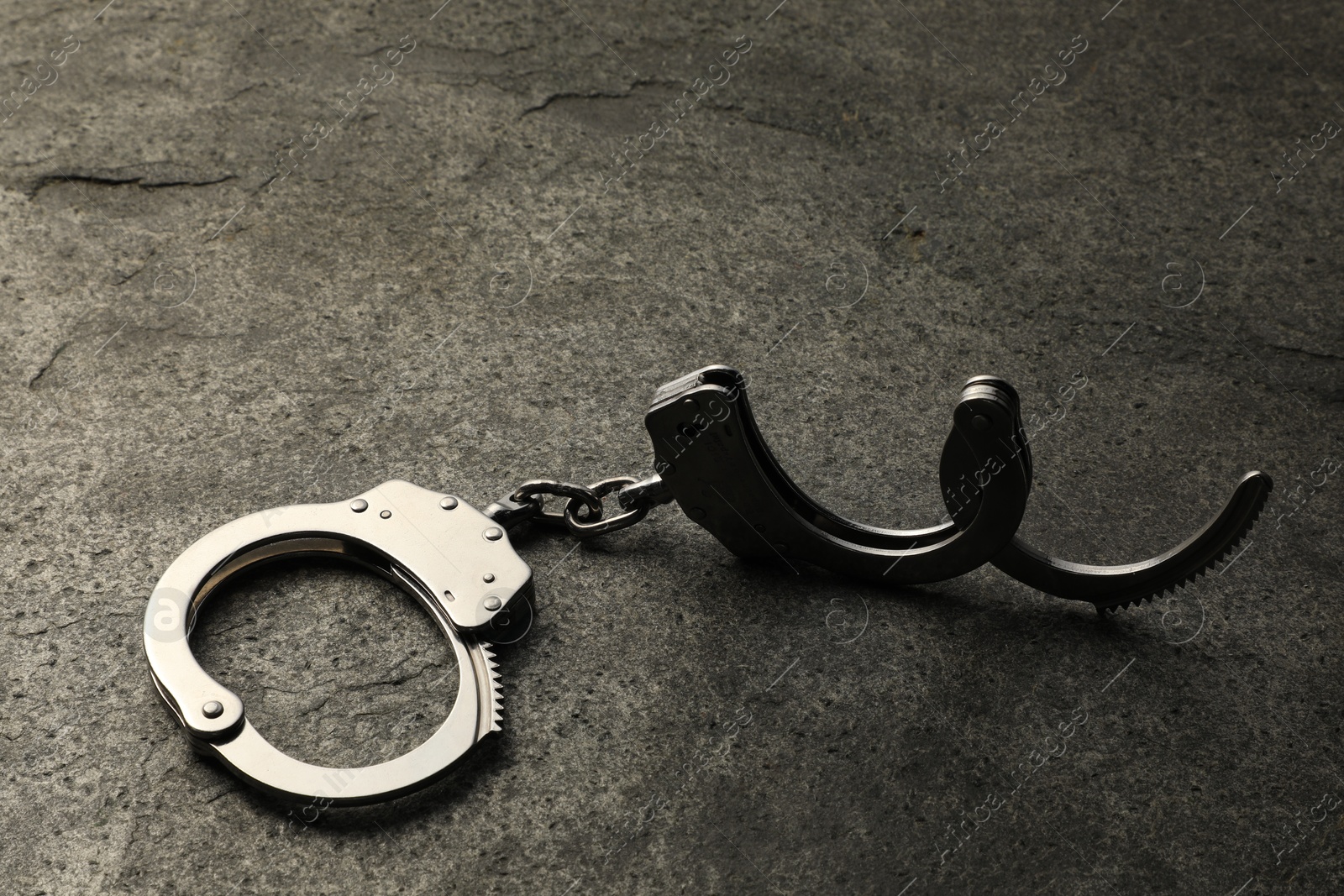 Photo of Classic chain handcuffs on grey table, closeup