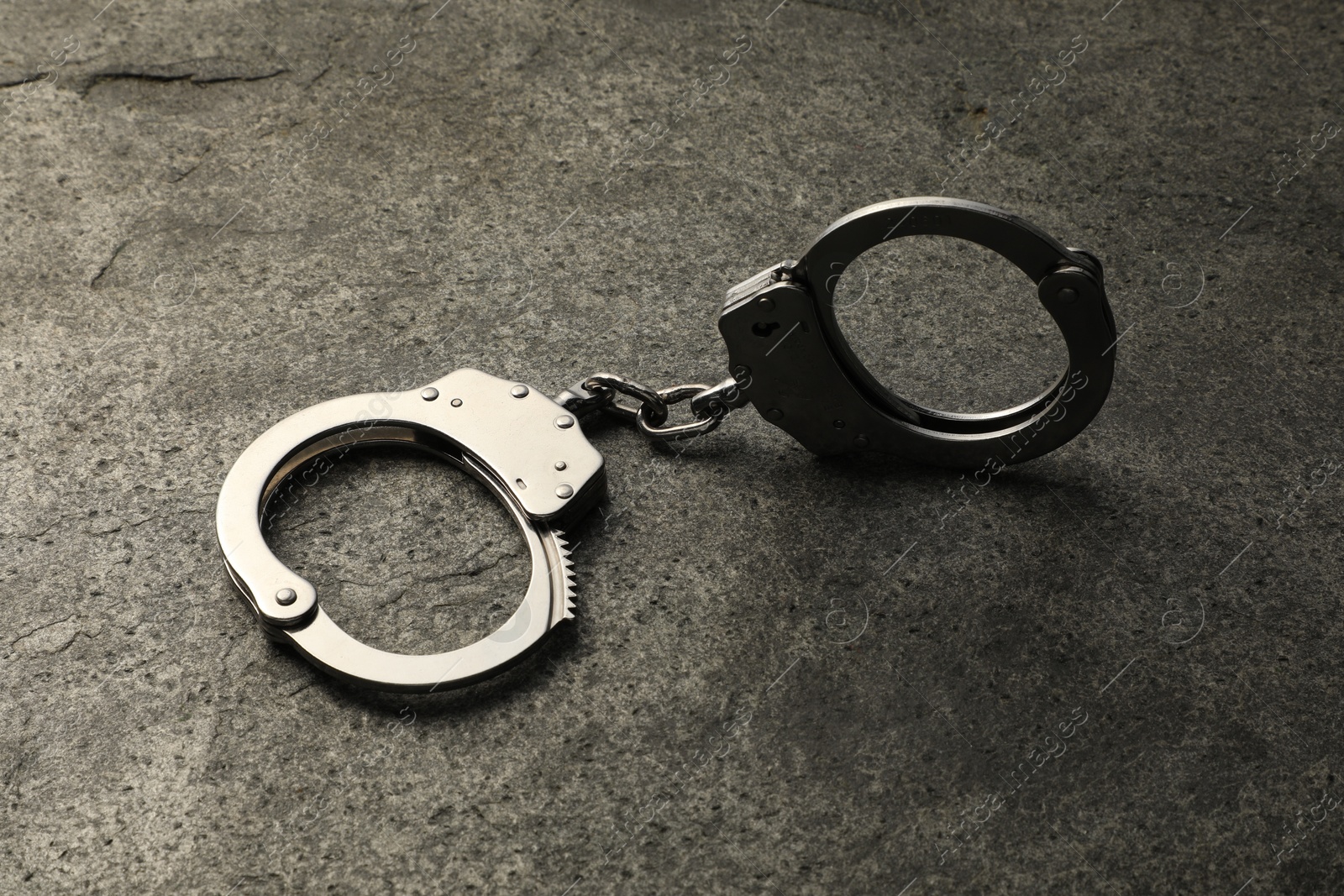 Photo of Classic chain handcuffs on grey table, closeup