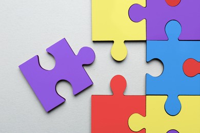 Many colorful puzzle pieces on light grey background, top view. Symbol of autism