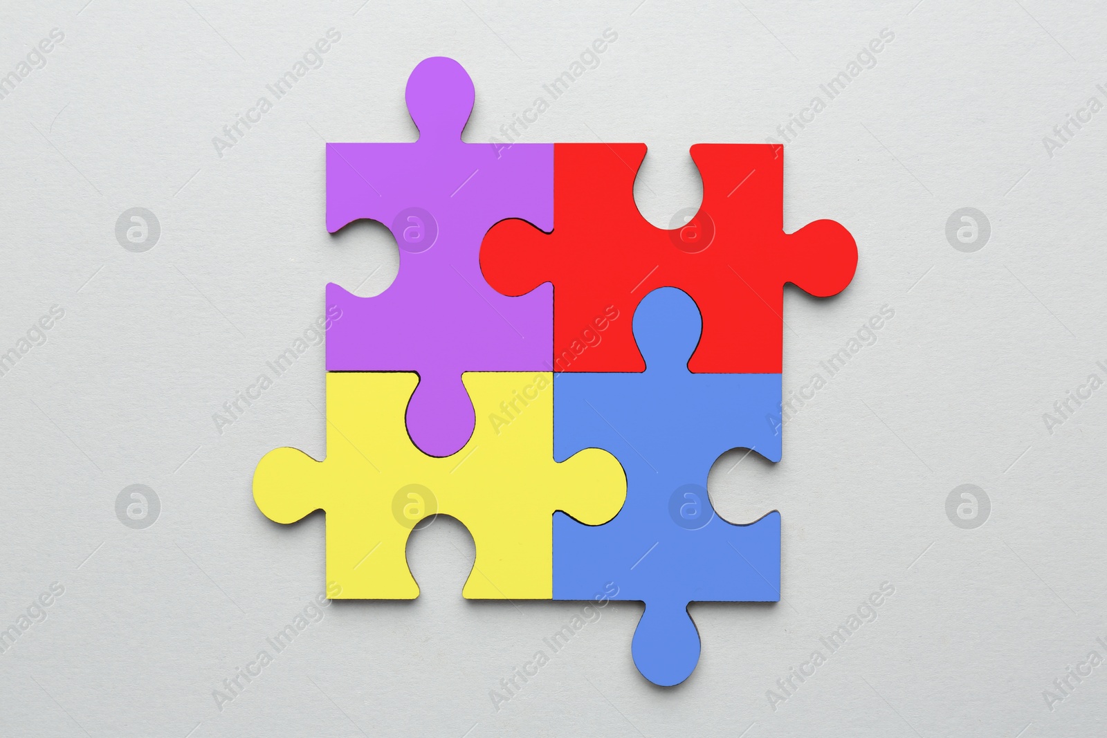 Image of Four colorful puzzle pieces on light grey background, top view. Symbol of autism