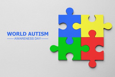 Image of World Autism Awareness Day text and colorful puzzle pieces on light grey background, top view