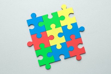 Image of Many colorful puzzle pieces on light grey background, top view. Symbol of autism