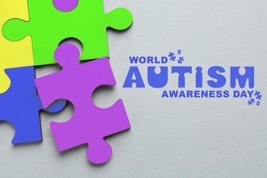 World Autism Awareness Day text and colorful puzzle pieces on light grey background, top view