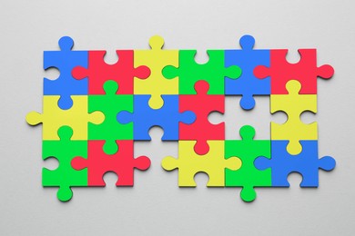 Image of Many colorful puzzle pieces on light grey background, top view. Symbol of autism