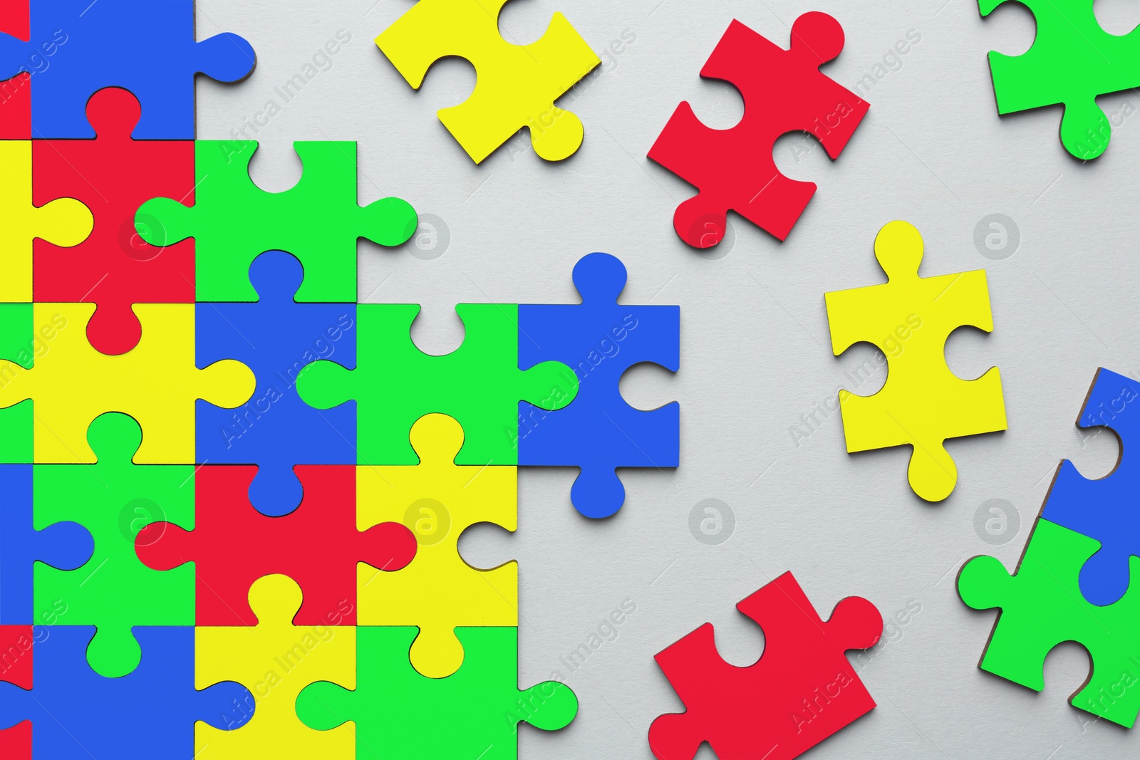 Image of Many colorful puzzle pieces on light grey background, top view. Symbol of autism