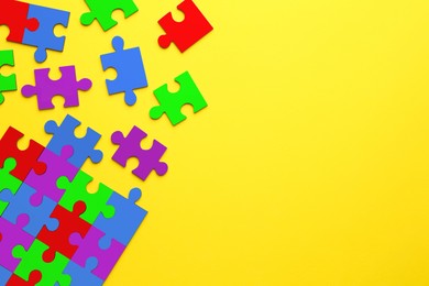 Image of Many colorful puzzle pieces on yellow background, top view. Symbol of autism