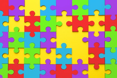 Image of Many colorful puzzle pieces on yellow background, top view. Symbol of autism