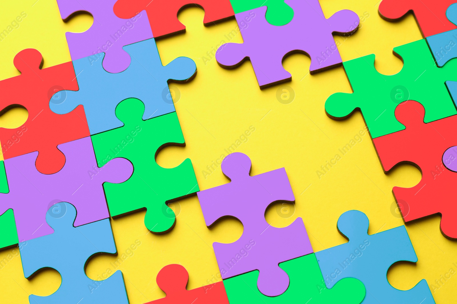 Image of Many colorful puzzle pieces on yellow background. Symbol of autism