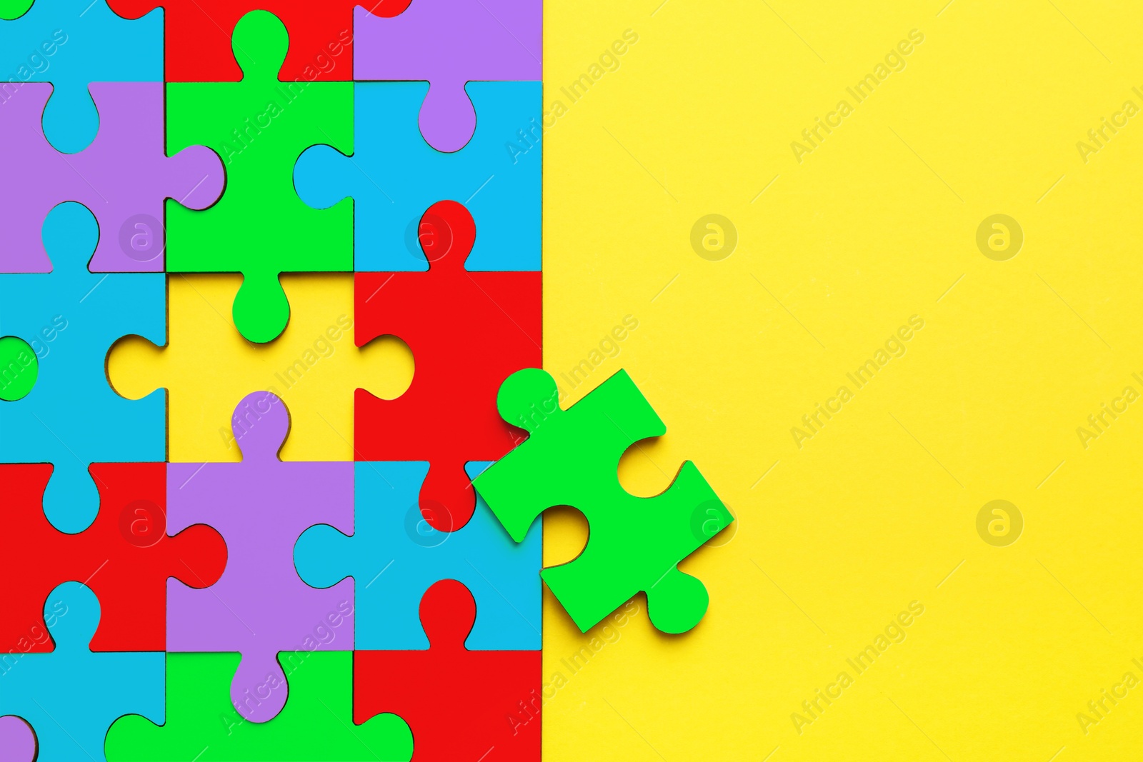 Image of Many colorful puzzle pieces on yellow background, top view. Symbol of autism