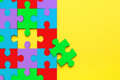 Image of Many colorful puzzle pieces on yellow background, top view. Symbol of autism