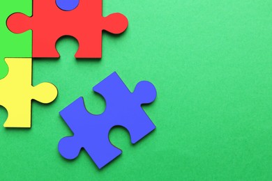 Image of Colorful puzzle pieces on green background, top view. Symbol of autism