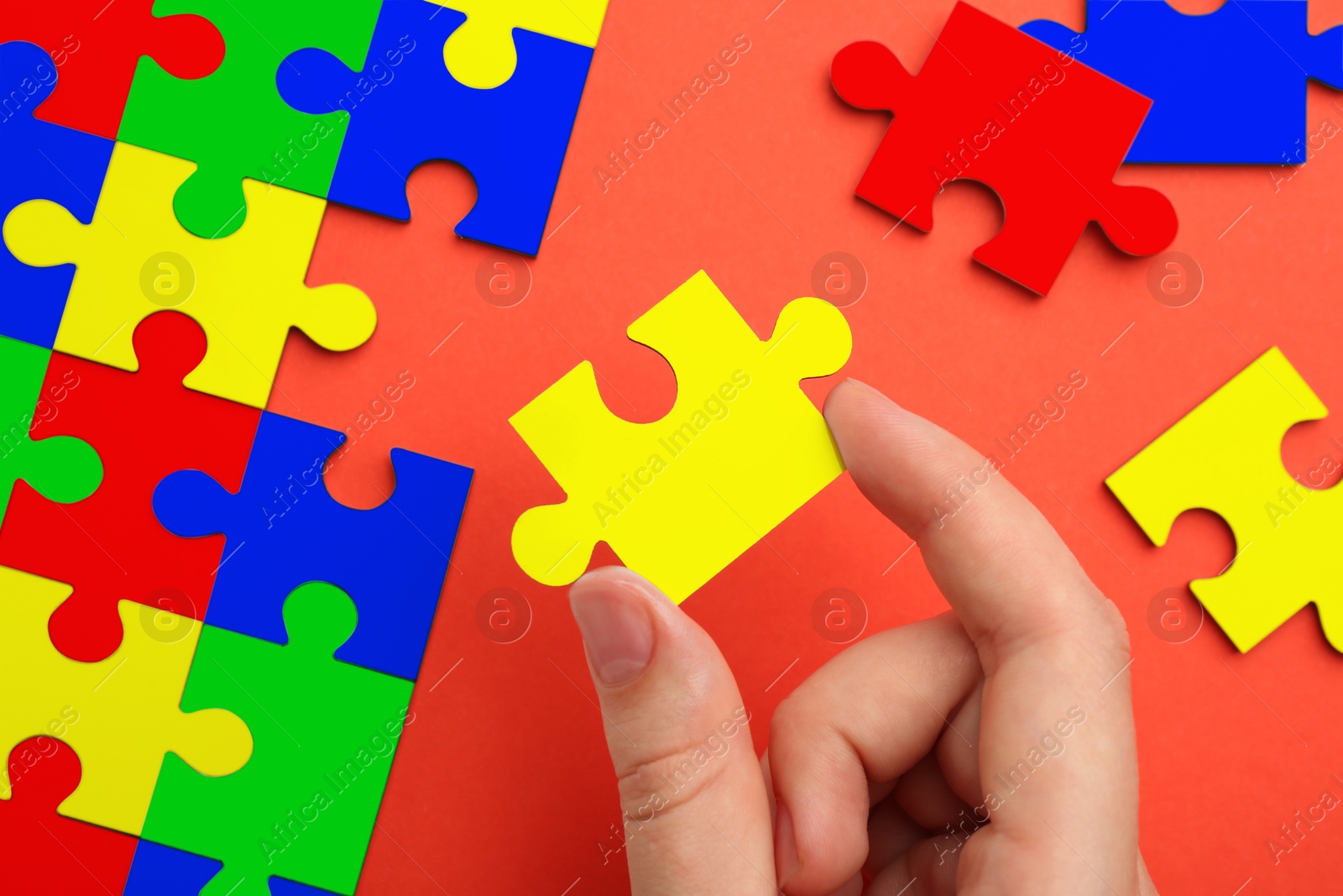 Image of Woman holding puzzle piece on red background, top view. Autism concept