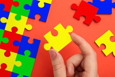 Image of Woman holding puzzle piece on red background, top view. Autism concept