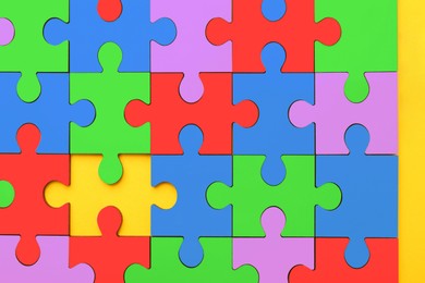 Image of Many colorful puzzle pieces on yellow background, top view. Symbol of autism